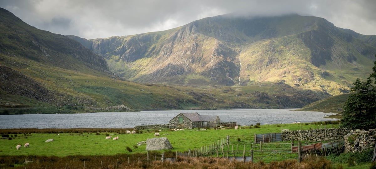 Llyn Ogwen onder een bewolkte lucht waarbij de zon gedeeltelijk doorbreekt en licht en schaduw over het water speelt