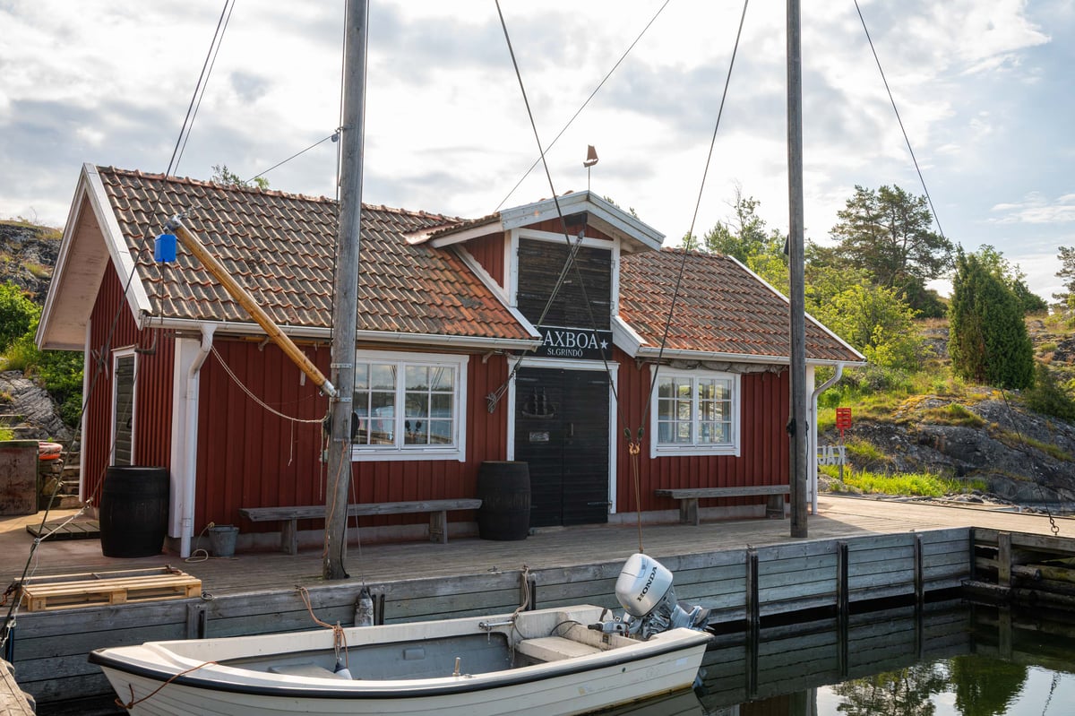 Het rode havengebouwtje van Axboa op de steiger bij Stora Grindö, met een afgemeerde motorboot op de voorgrond