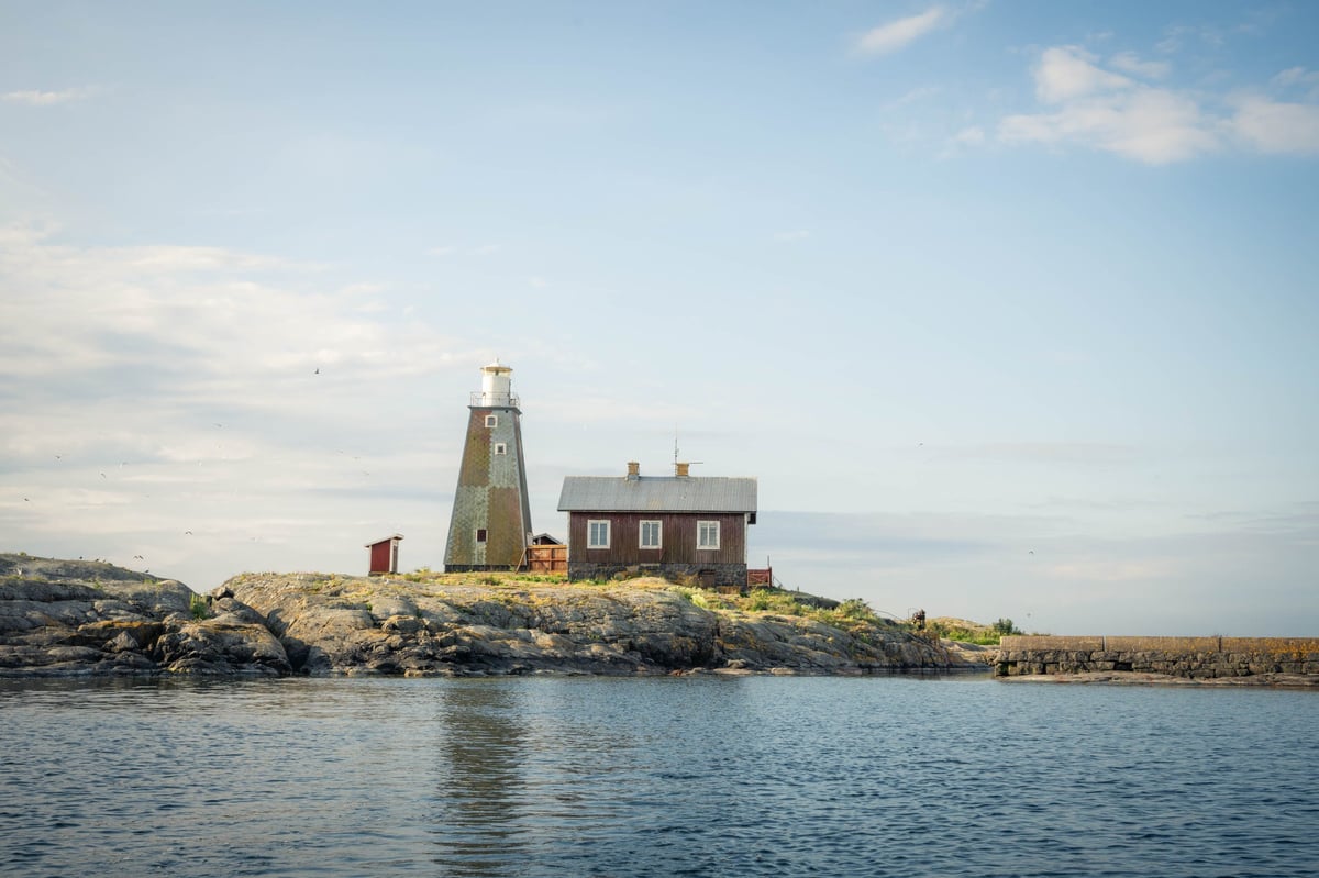 Vuurtoren van Storkläppen gezien vanaf het water — een centraal-symmetrische compositie met het rotseiland als sokkel