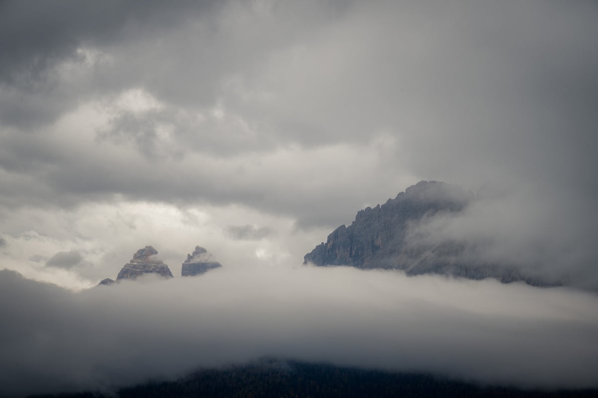 Bergtoppen die amper zichtbaar zijn door een dik wolkendek op een bewolkte dag in de Alpen.
