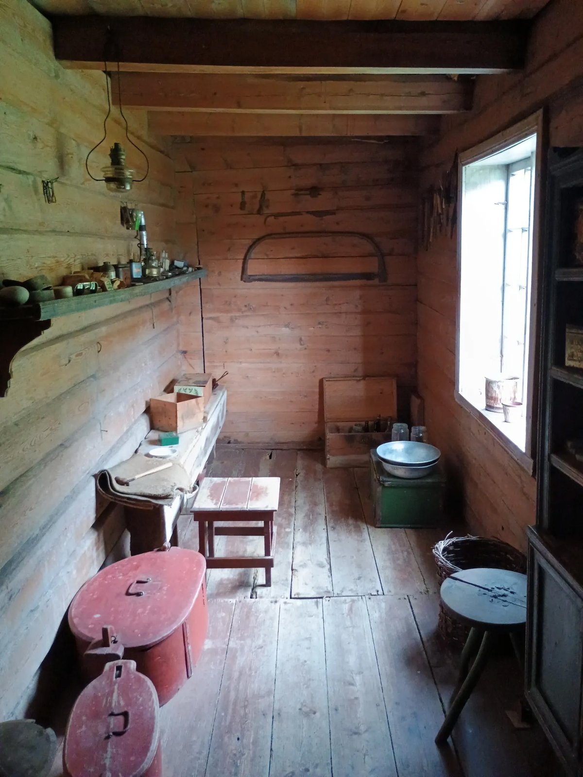 Interieur van een historische blokhut met antieke gebruiksvoorwerpen, olielamp en houten meubels op Jonegarden