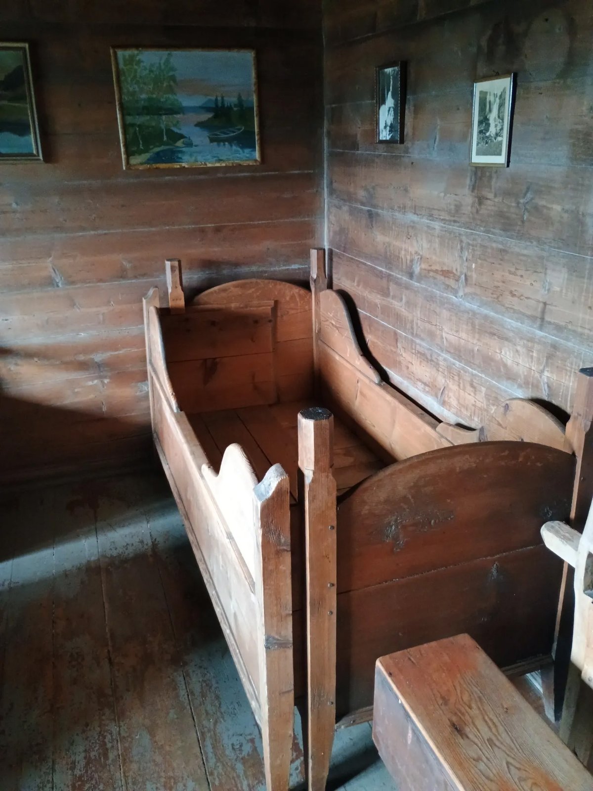 Twee oude houten bedsteden in de hoek van een rustieke donkere houten boerderijkamer met schilderijen aan de wand op Jonegarden