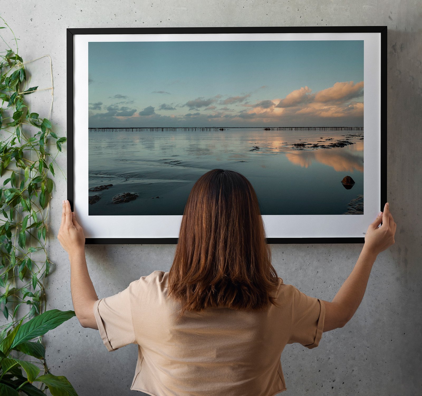 woman hanging fine art print in living room