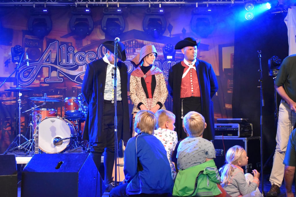 Costumed performers on stage entertain children at outdoor festival.
